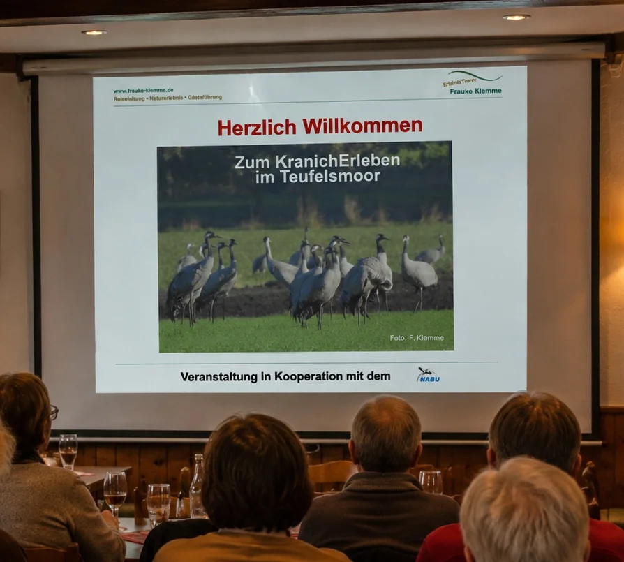 Menschen schauen auf eine Leinwand mit Kranich-Vortrag