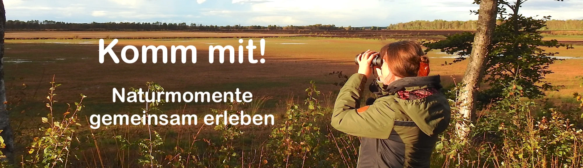 Frau schaut mit Fernglas in die Natur